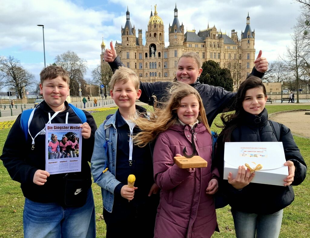Die Redakteure Phil, Louis, Heidi, Eleen und ihre Kursleiterin Michelle Freudenreich (hinten) mit Pokal und Preisen vor dem Schweriner Schloss. Foto: A. Farin