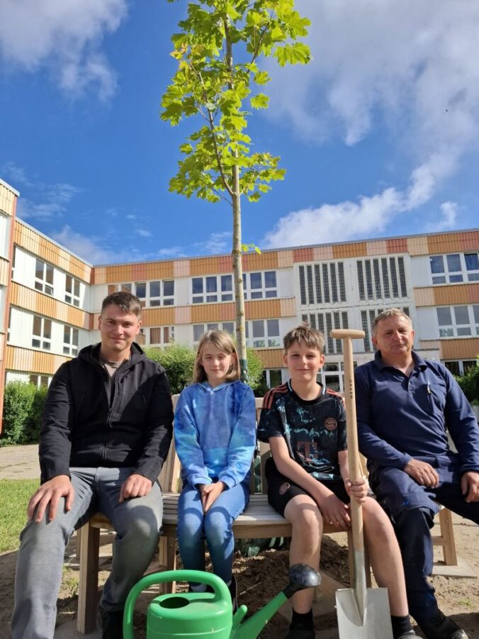 Unterm Klimabaum sitzen Ida Andreas und Marten Briesemeister aus der 4. Klasse mit Baumschul-Chef Max Kieker (links) und Hausmeister Ulf Hensel an der Investition der Grundschüler. Foto: A. Farin