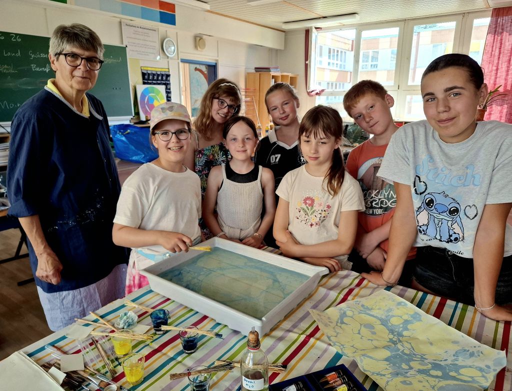 Kunstwerkstatt in der Schule Gingst. Petra Saal (links) zeigt ihren interessierten Sommerferien-Kindern das Marmorieren von Papier. Foto: André Farin